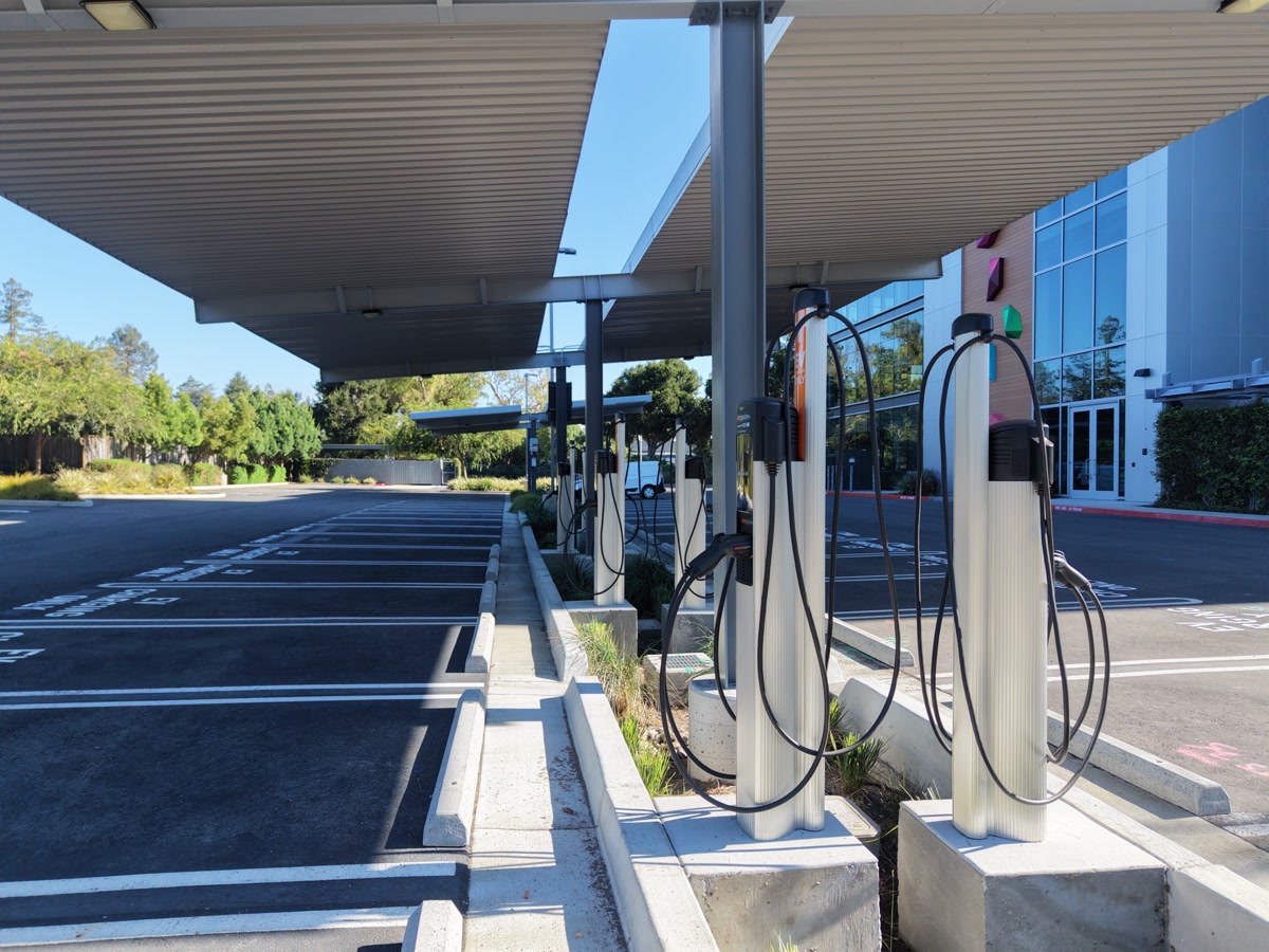 A row of commercial EV charging stations beneath a parking canopy